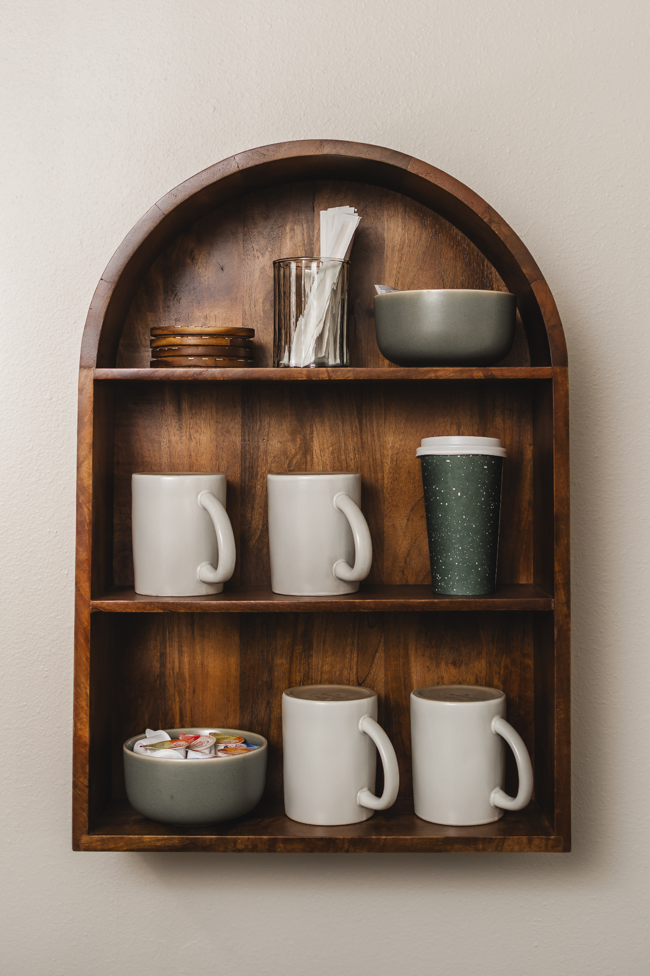 Warm wooden shelf with mugs, coasters, and coffee station at Jenna Lauren Hair Designs studio