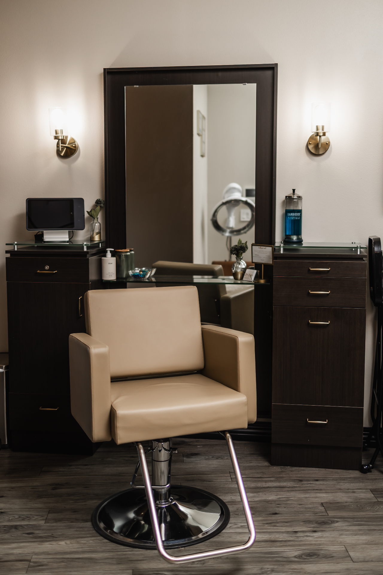 Tan leather styling chair in front of a tall mirror with brass sconces at Jenna Lauren Hair Designs studio in Innsbrook