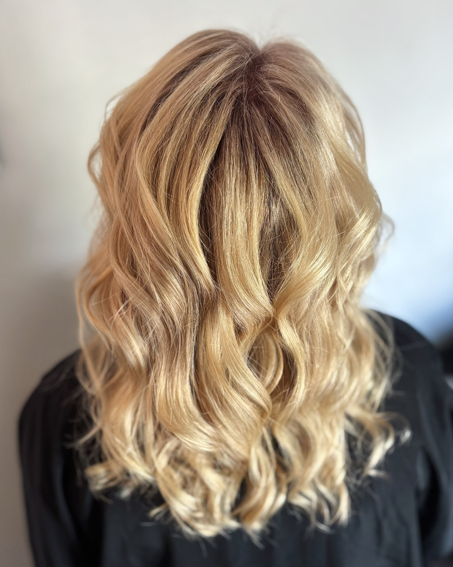 Creamy beige blonde highlights with seamless root melt styled in voluminous waves